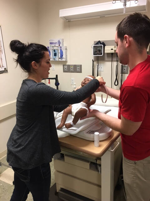 A student and instructor handle a pediatric manikin in an inpatient setting